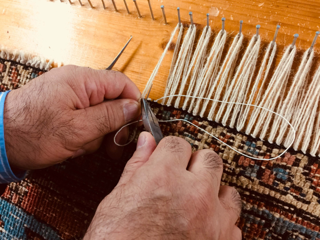 Fransenreparatur an einem Teppich in Handarbeit